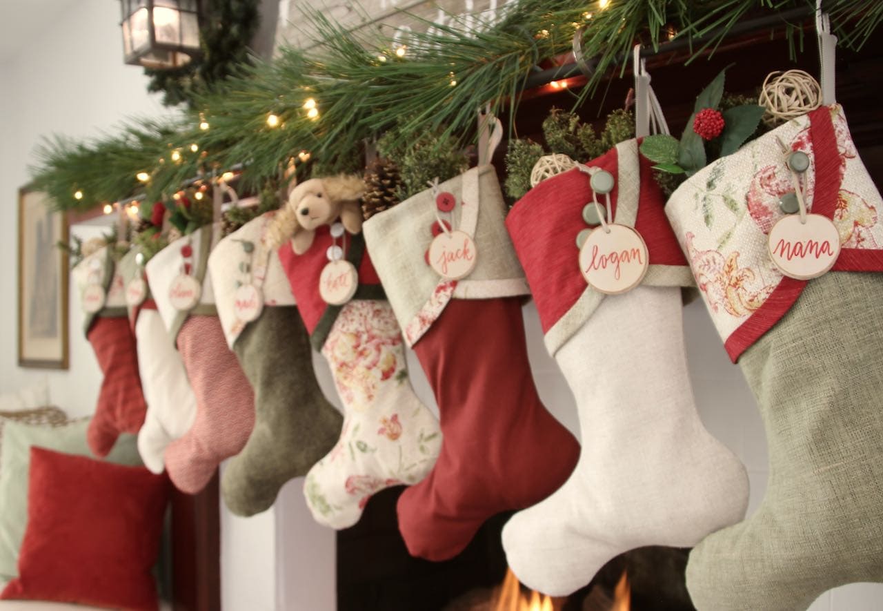 Cottage Christmas Stocking with birch tree slice name tags hanging from the top buttons on each stocking cuff