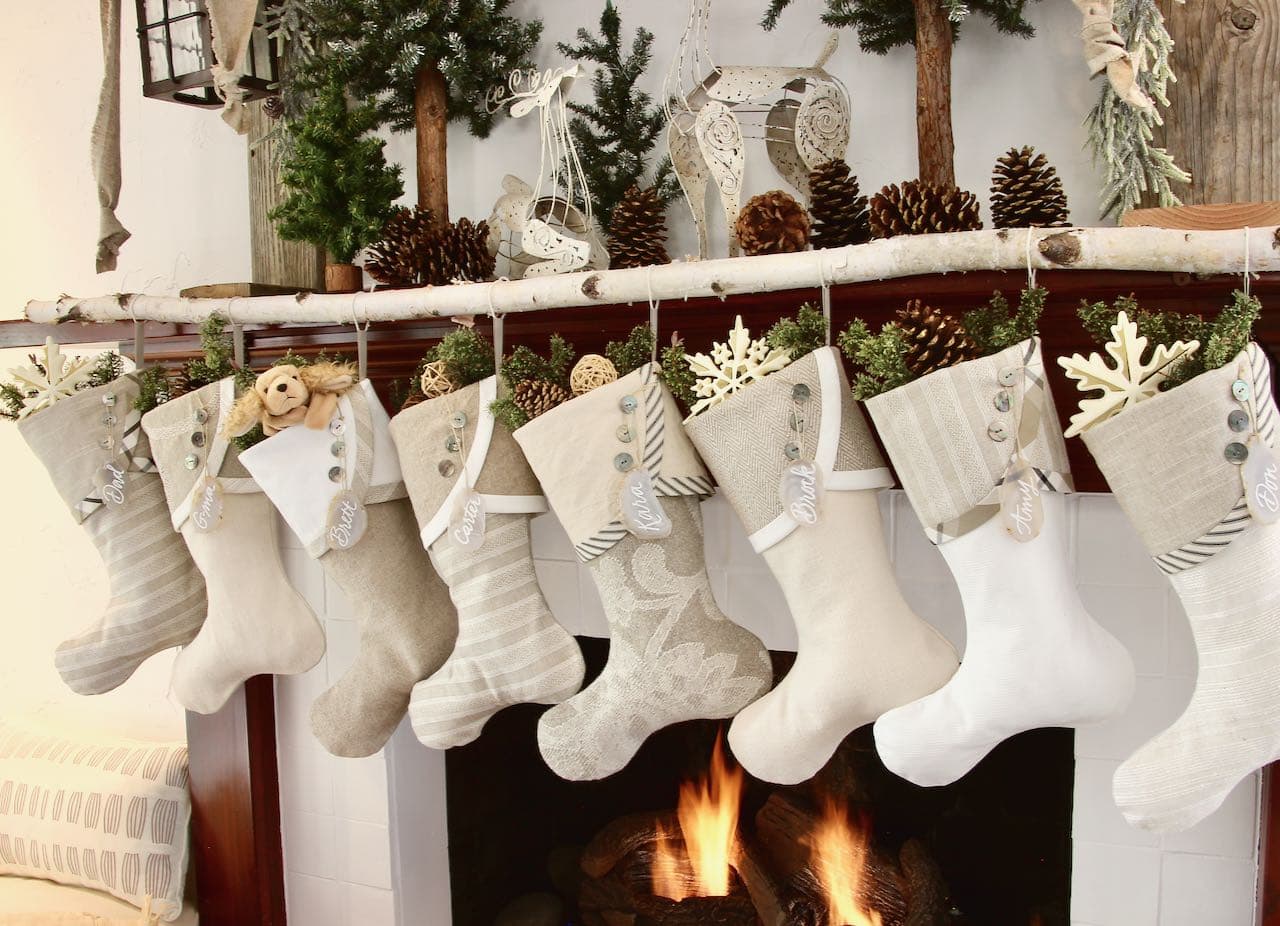 Neutral Farm house Christmas stockings with agate slice name tags hanging from a white birch limb