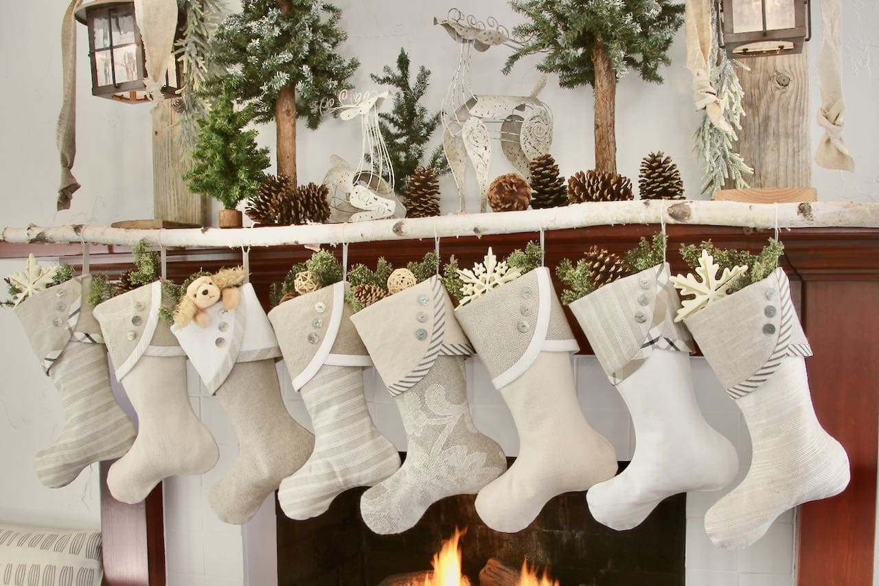 Neutral farmhouse Christmas stockings with no name tags hanging from a white birch tree branch