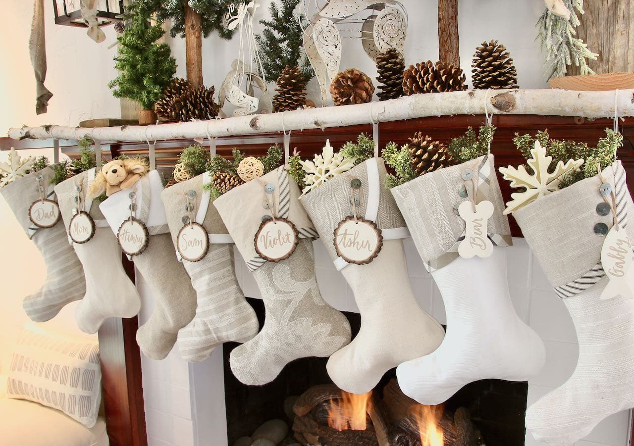 Farmhouse Christmas Stockings with white tree slice name tags hanging from a birch tree limb