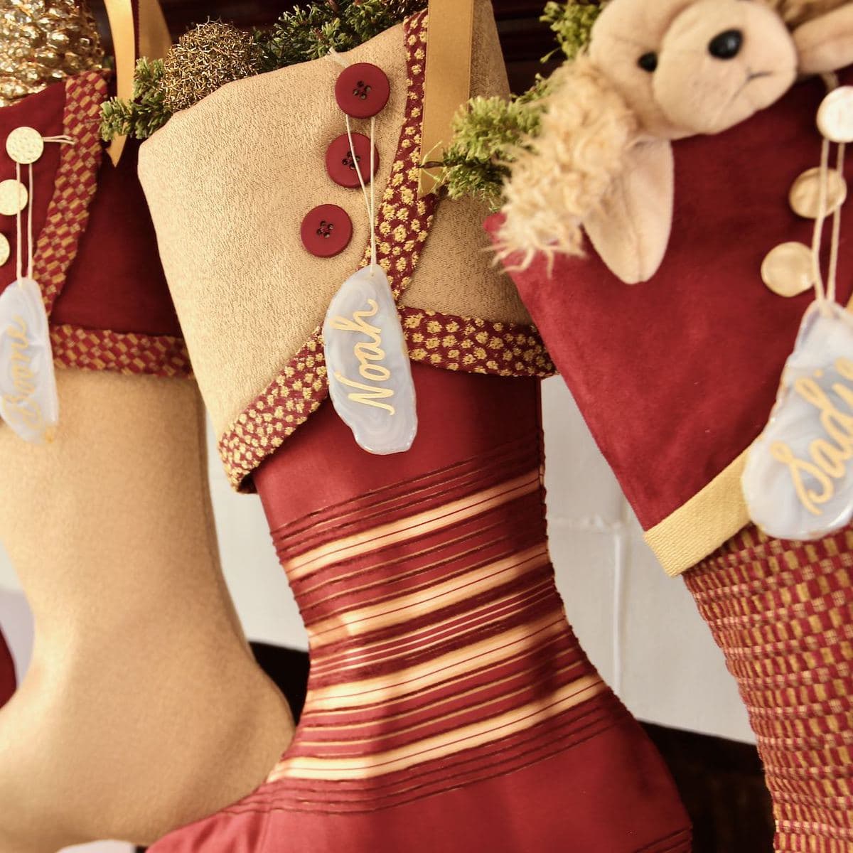 Closeup of thee red and gold Christmas stockings with agate name tags