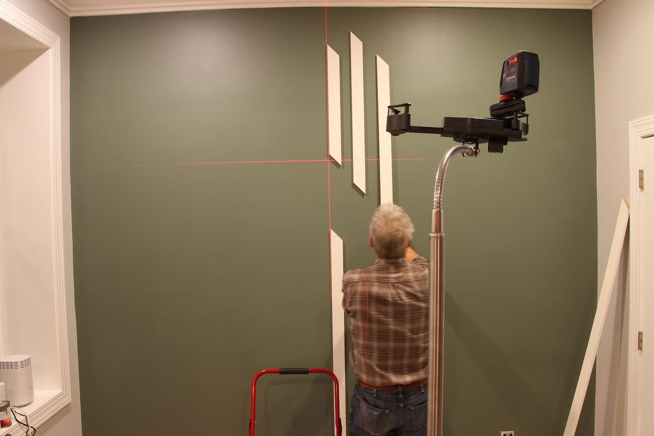 The feature wall shown with a lazer lever marking the vertical center point with the first accent board along that line and two more boards working towards the right