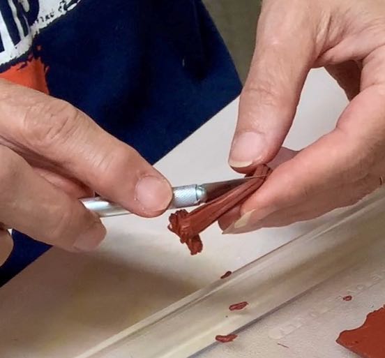 Hand with exacto knife cutting the stem bundle in half