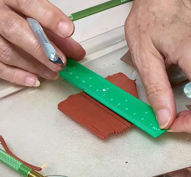 Hands with straight edge and exacto knife cutting a lot of slices