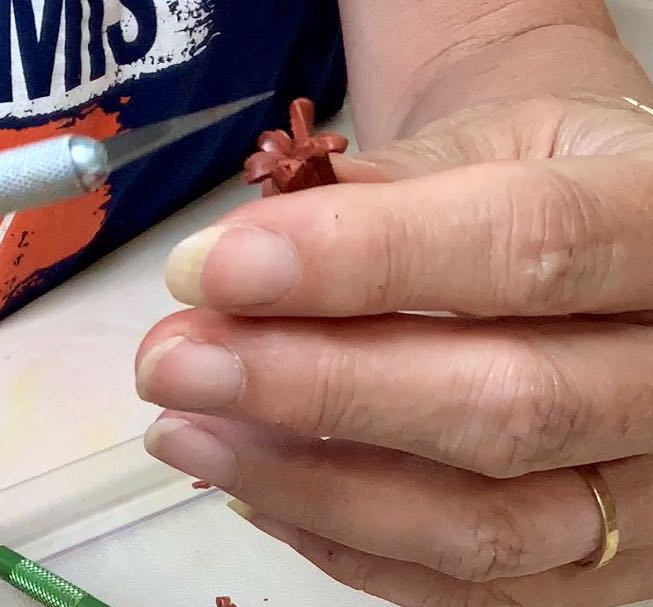 hand holding an exacto knife using the point to separate the tips of the slices