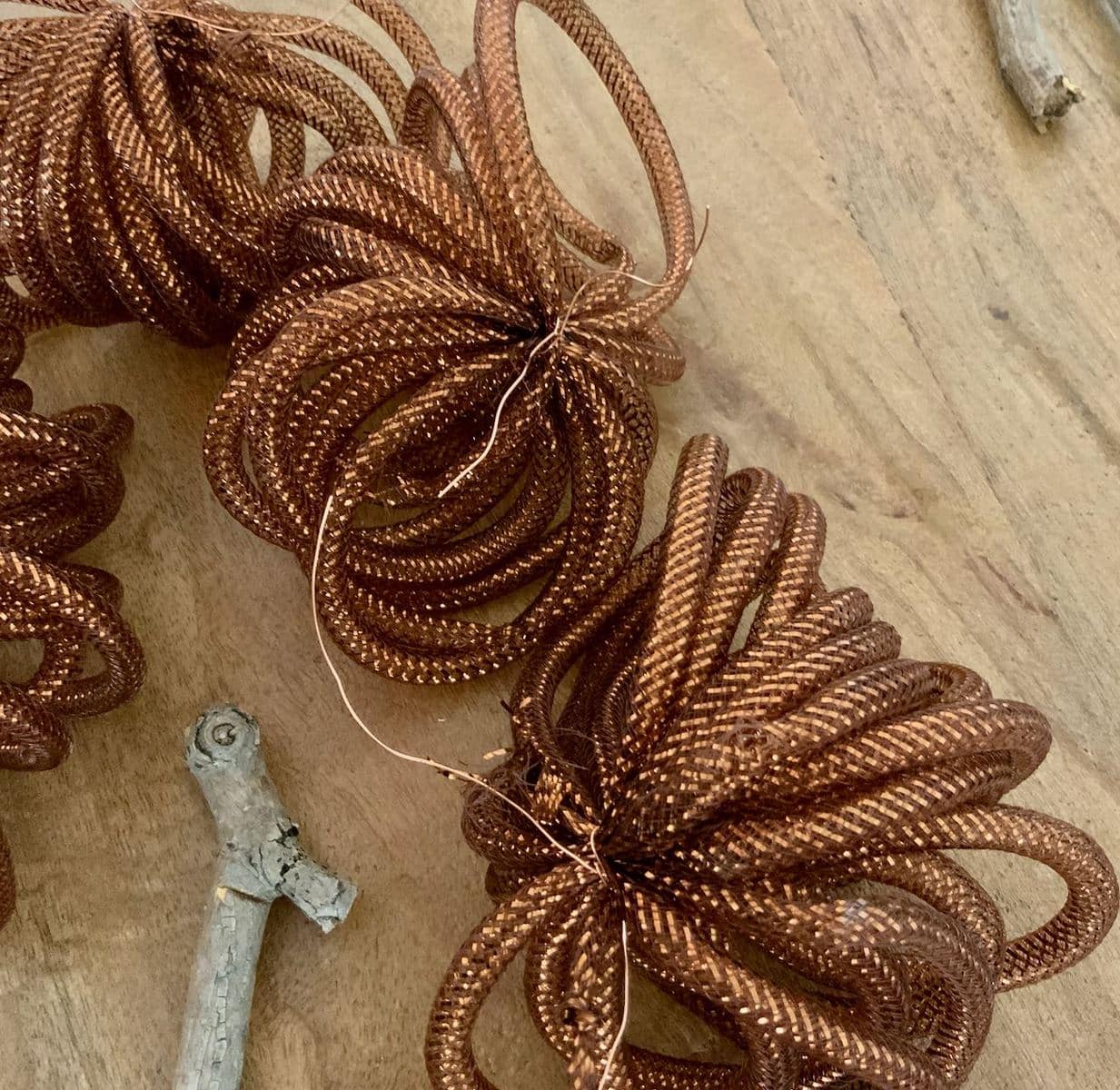 Four bundles of bronze mesh are shown on a table top around a stick