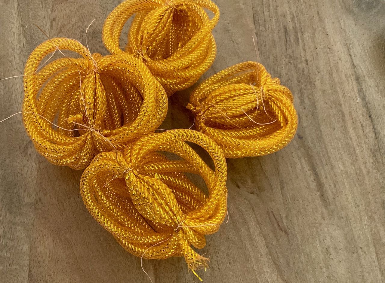 Four bundles of orange mesh tubing are shown on a wood table with all our bundles wired in two places