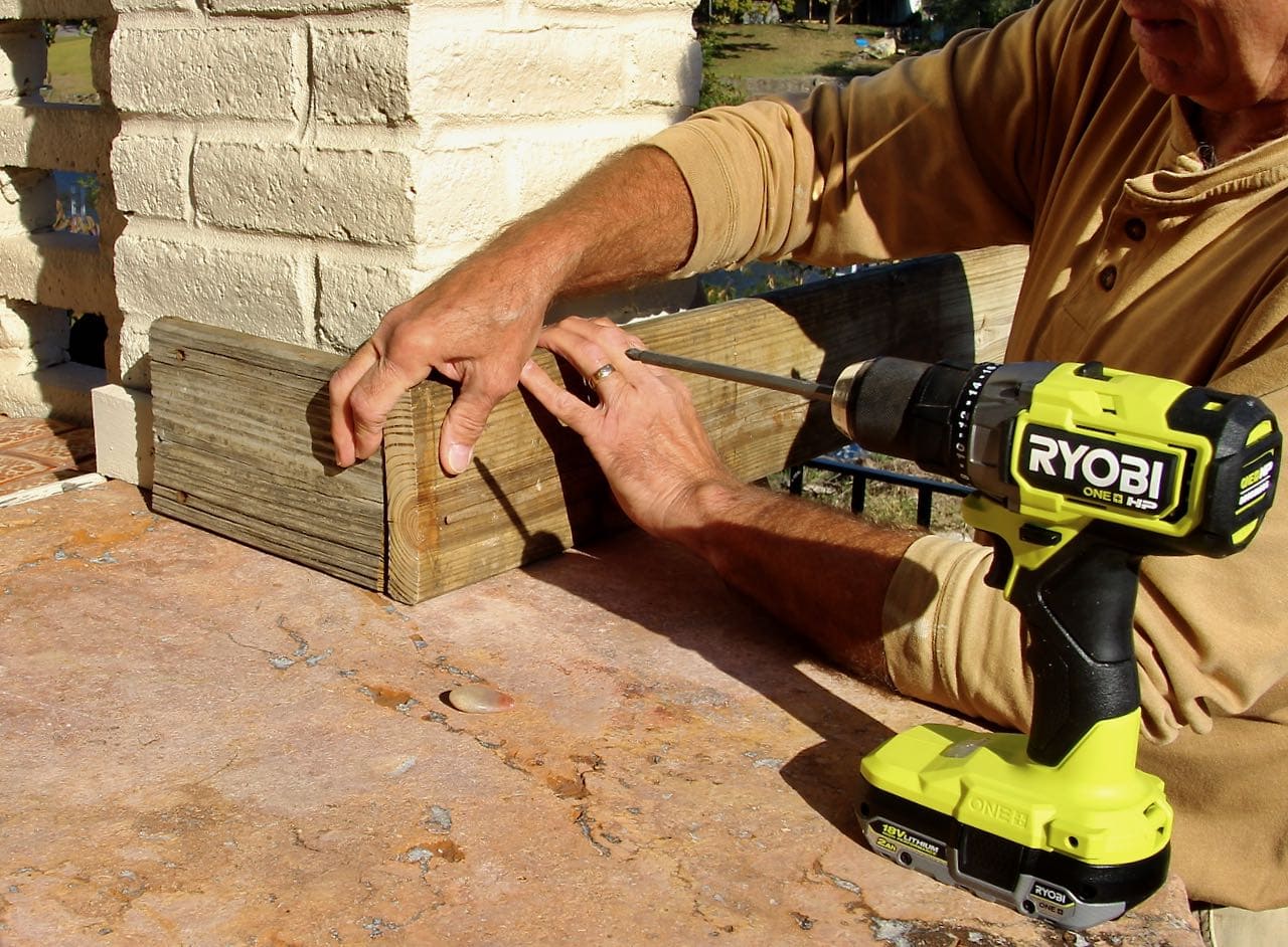 Pair of hands holding the two planks of wood to make a 90 degree angle