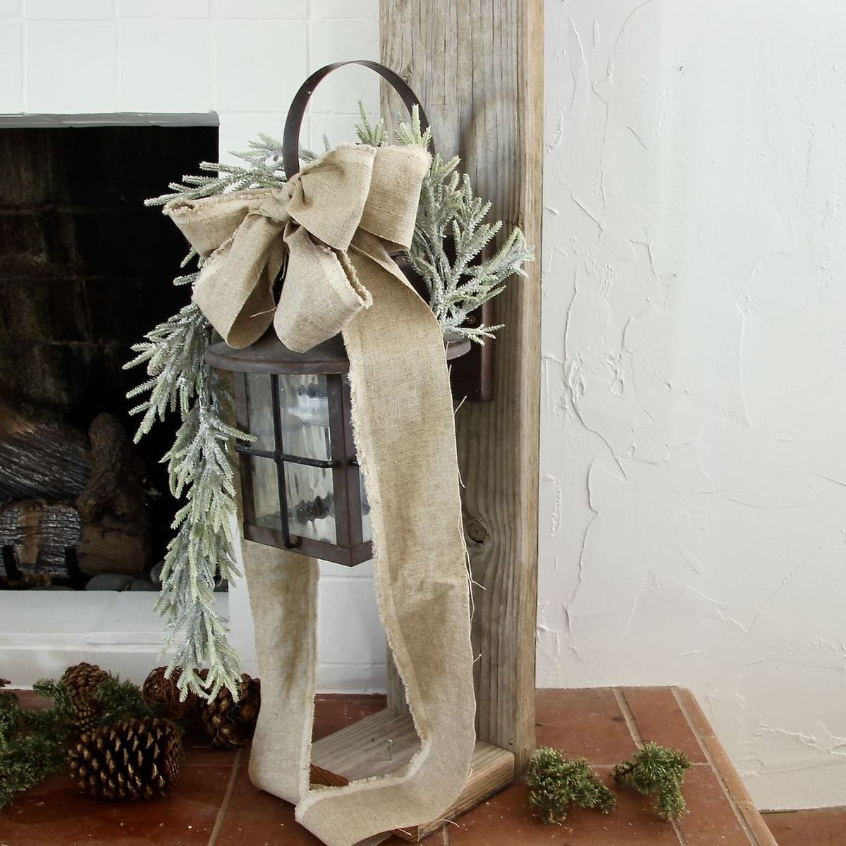 Vintage lantern hanging on a post with a linen bow and a length of greenery cascading from the top of the lantern