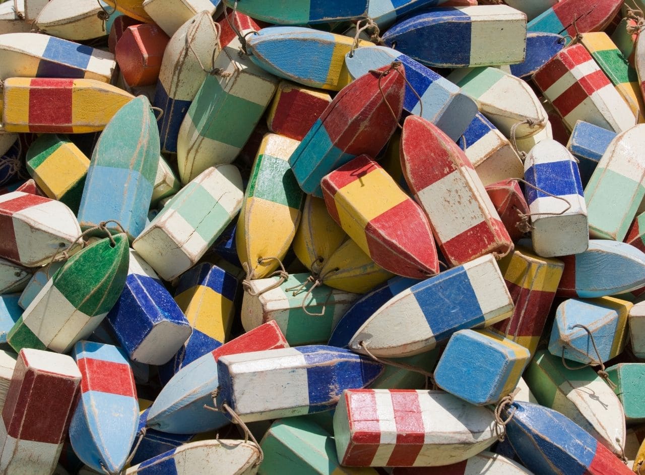 pile of old wooden buoys with lots of faded colors and rope handles