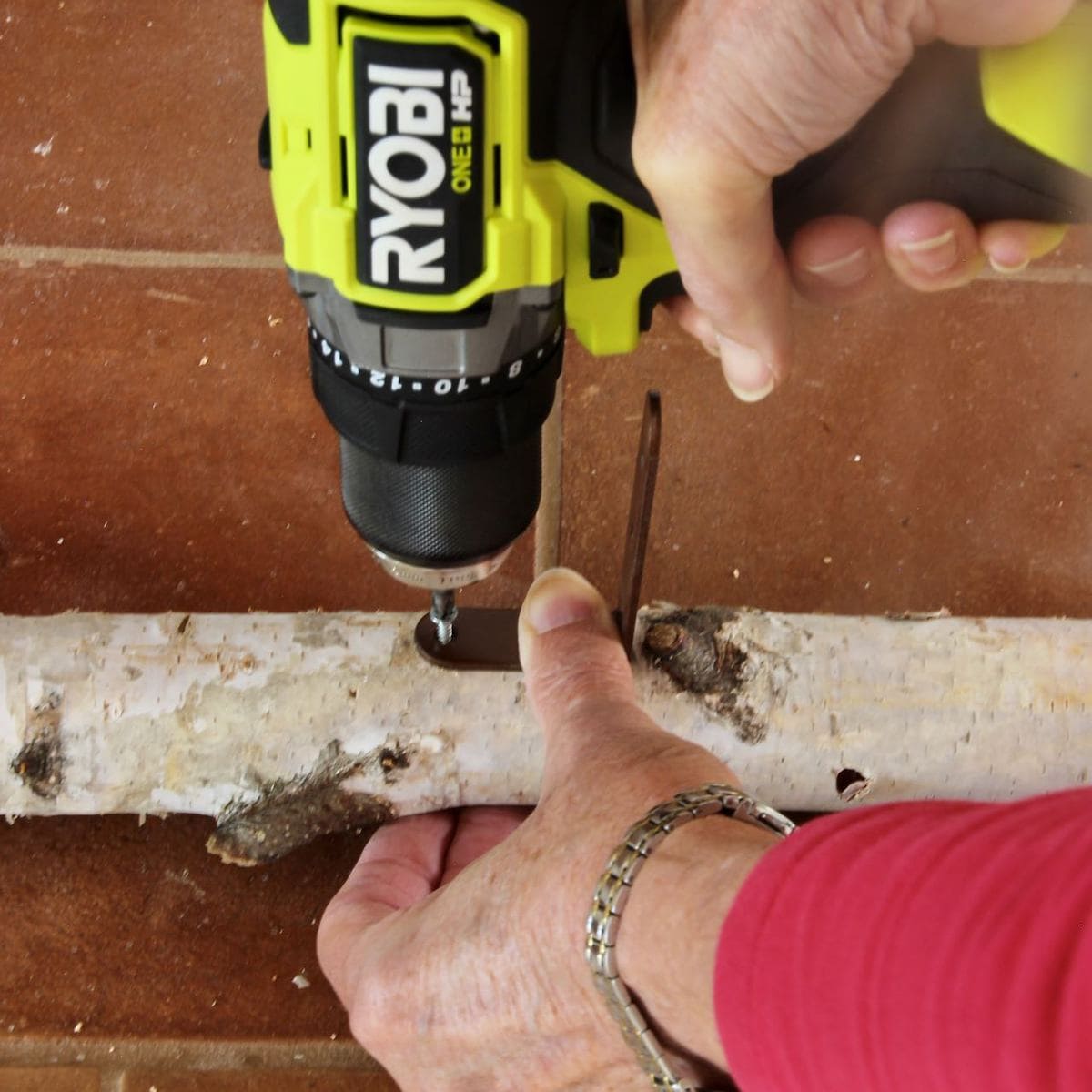 Closeup of driving screws into birch branch with Ryobi drill