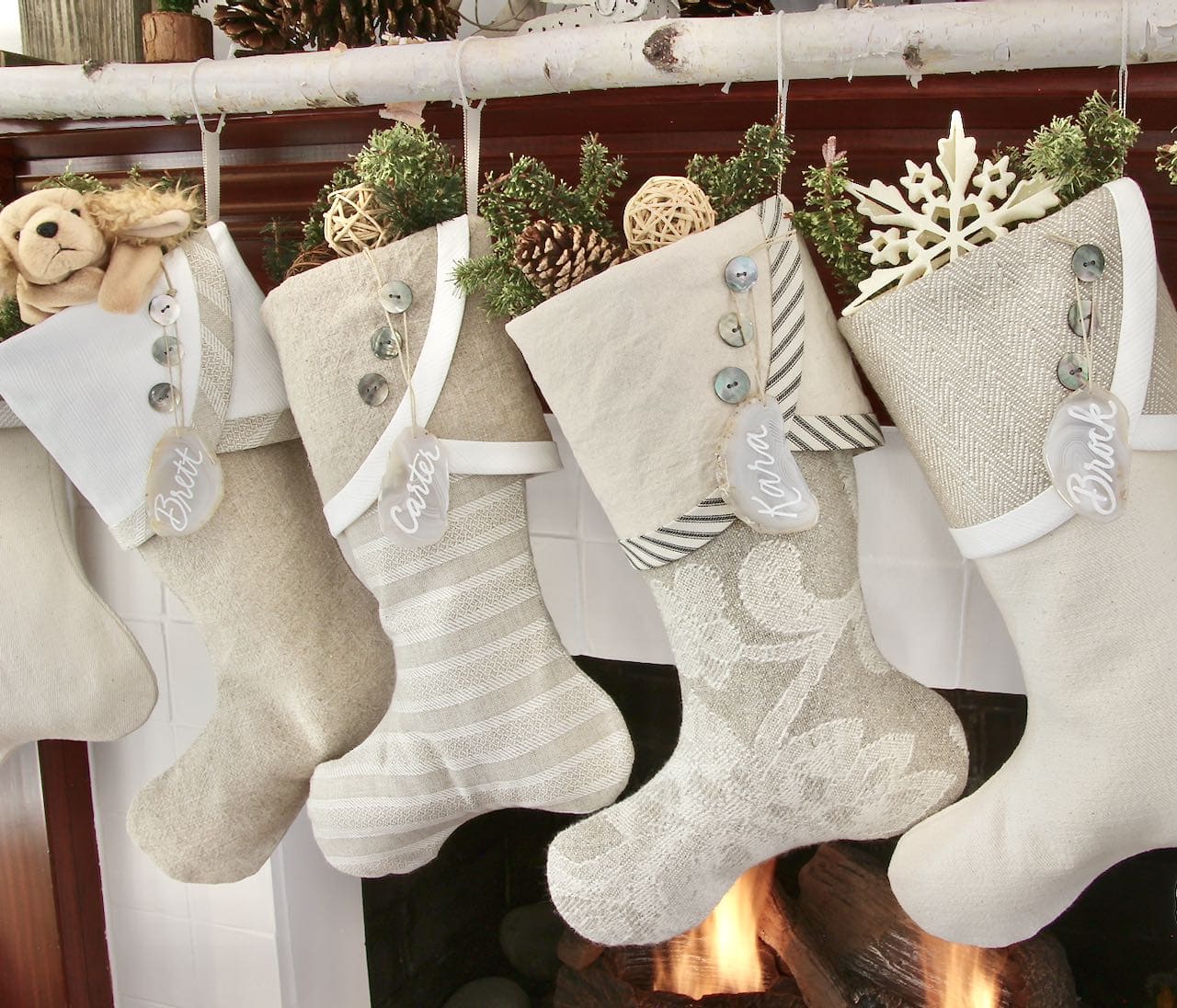 closeup of four of the Farmhouse Christmas stockings with agate name tags hanging from the birch branch
