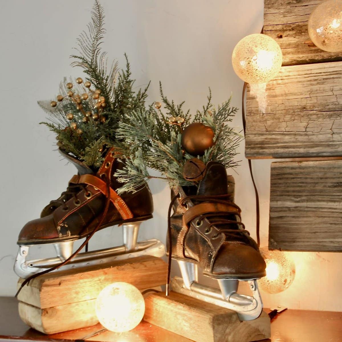 Closeup of pair of vintage ice skates mounted on wood block on a mantel with snowball lights around