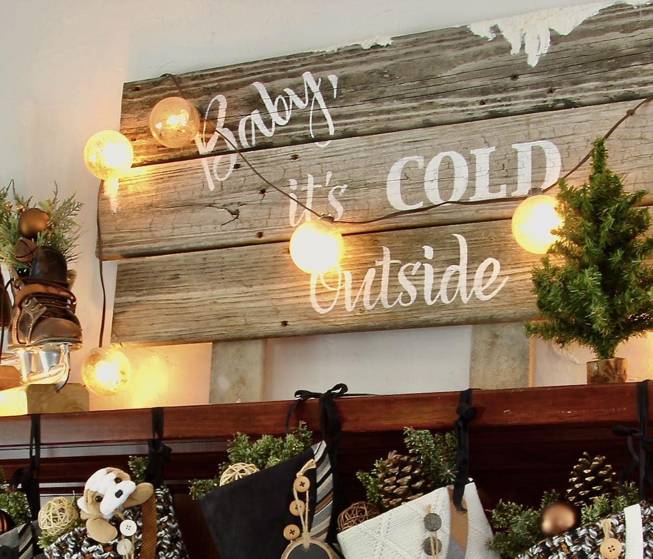 angled closeup of Baby it's cold outside sign with snowball lights draped loosely over the sign