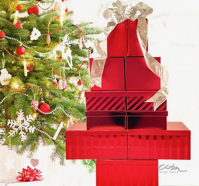 A tower of small gift boxes stacked like a tree with a live Christmas tree behind