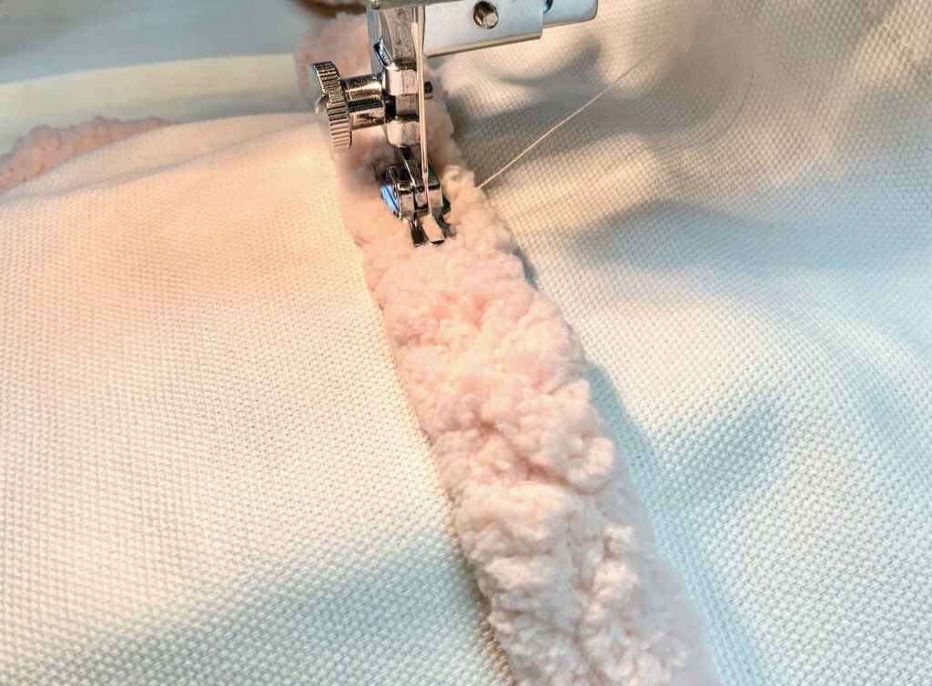 Presser Foot and Needle os Sewing Machine stitching down the center of the yarn onto the Valentine Pillow