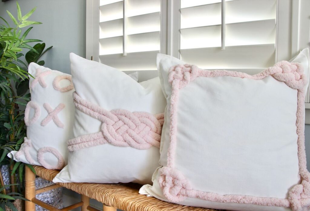 Trio of coordinating Valentines Day Pillows on a bench with white shutter behind