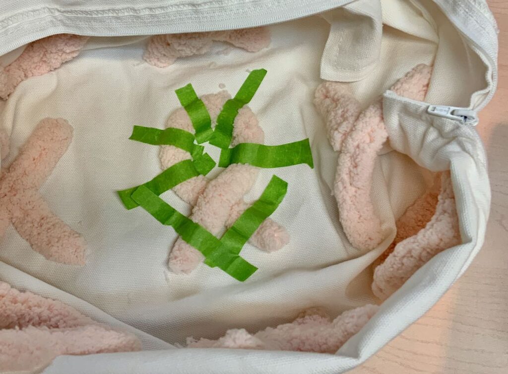 View into the pillow cover turned partially inside out forming. a bowl with the base holding the cancer ribbon yarn held in place with Painter's Tape