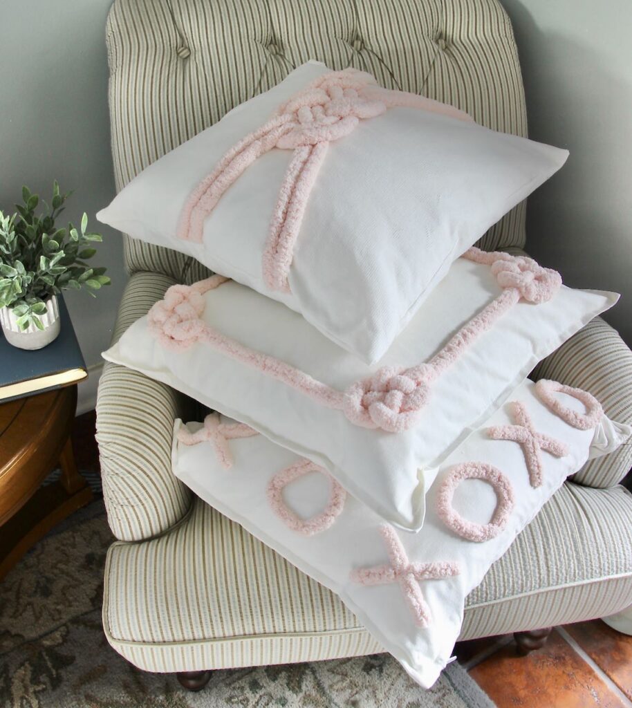 Three Valentines Day pillows stacked in a striped chair