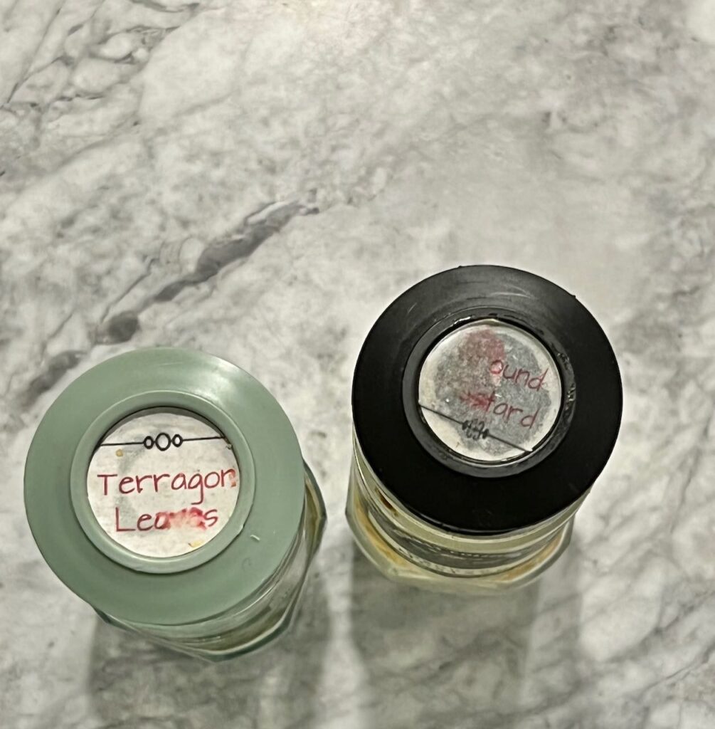 Closeup of two spice bottles with labels on the lids that can hardly be read due to water and grease stains
