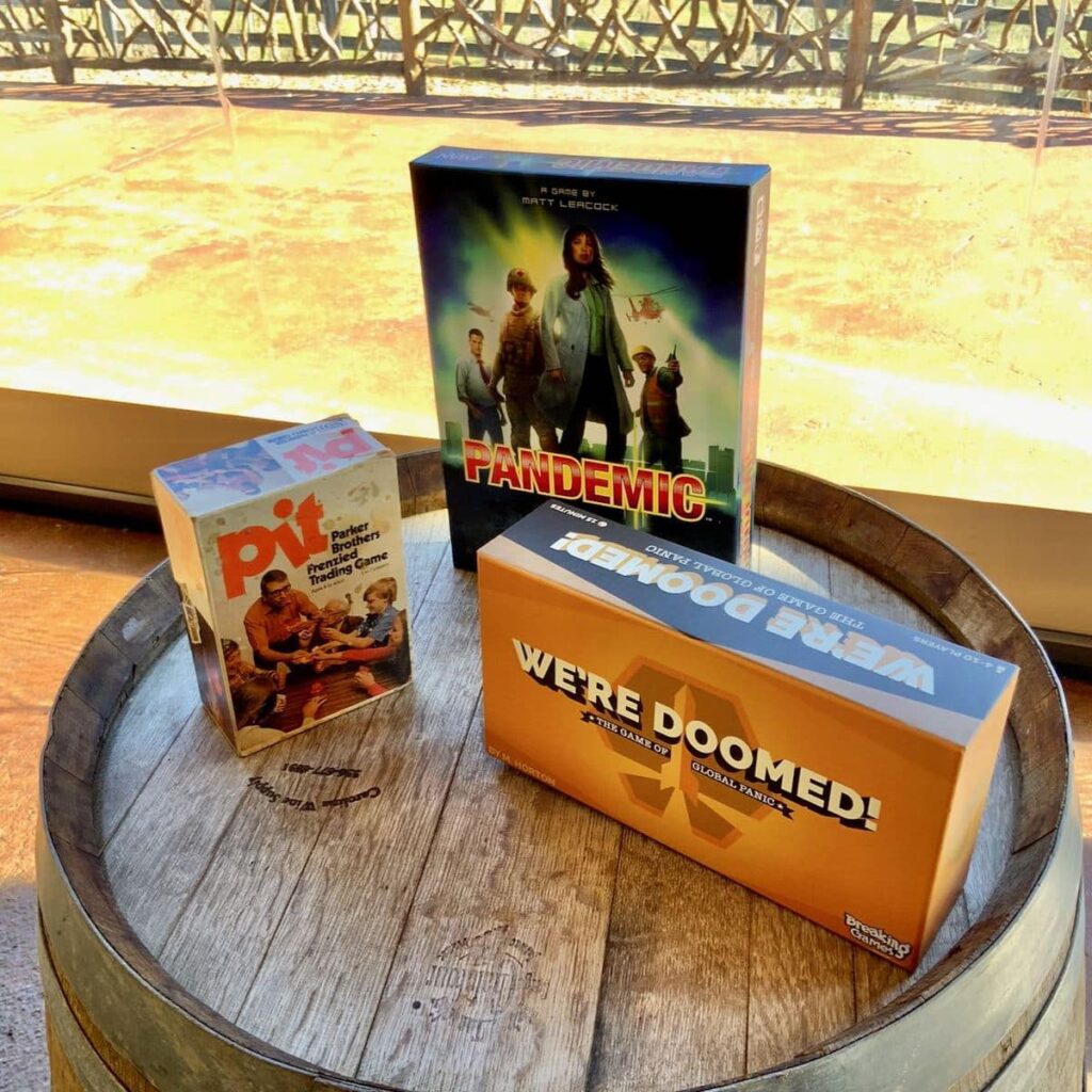 Three board games displayed on top of a wine barrel at Friendsgiving