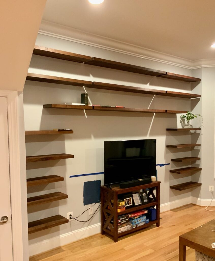 675 feet of almost empty floating bookshelves are installed with a TV and small cabinet centered where the cabinets will be.