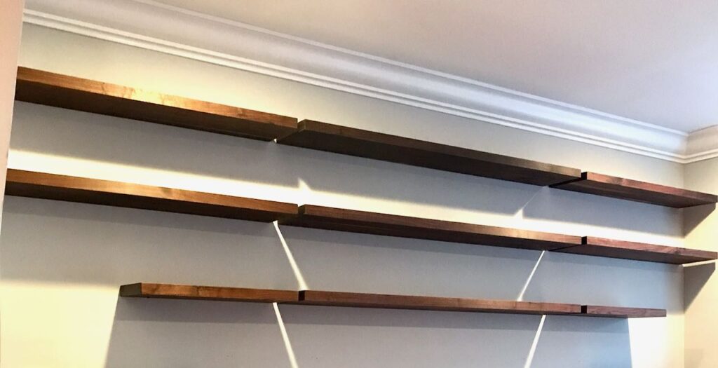 three rows of empty floating walnut shelves showing how the alignment is between