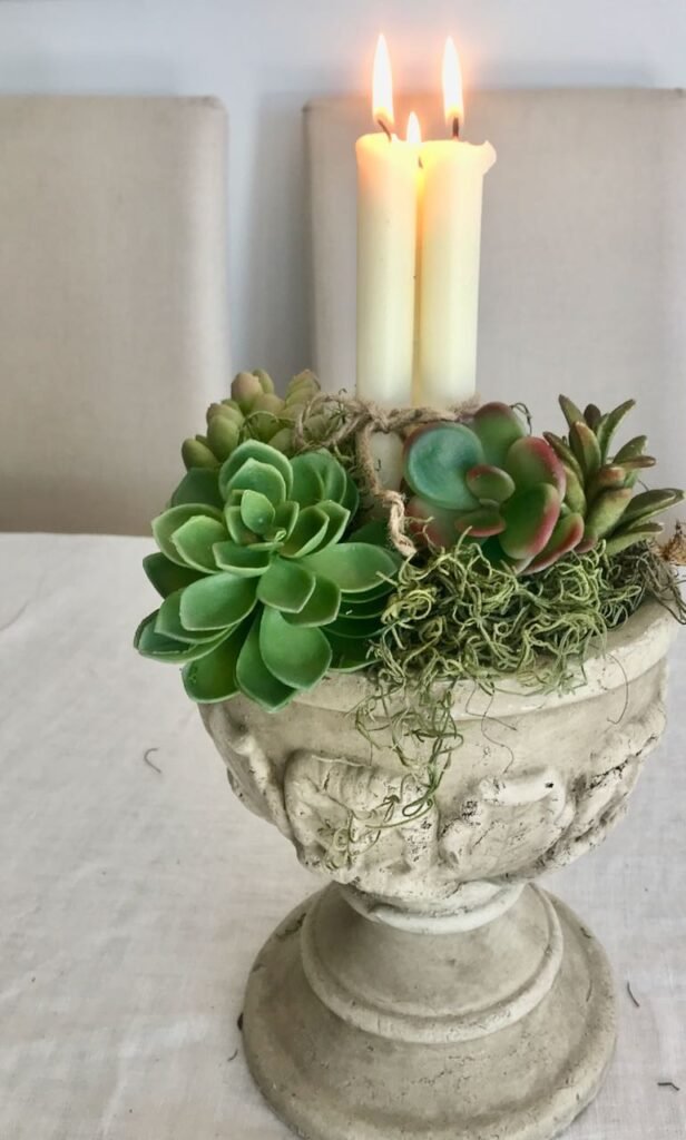 Lit Candle Bundles surrounded byu moss and succulents in a concrete urn