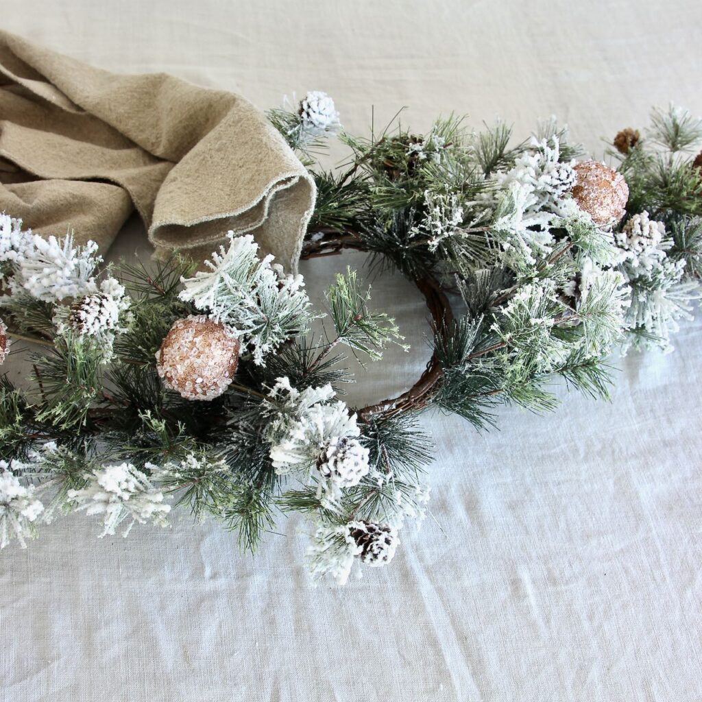 The candle ring with the end of one linen runner starting to be pulled through the top opening