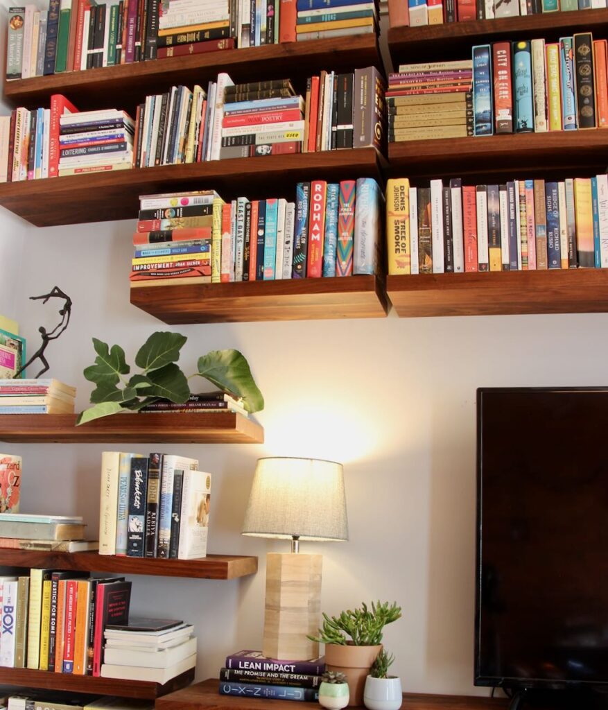 Partial view of the corner of a tv with floating shelves and books around it