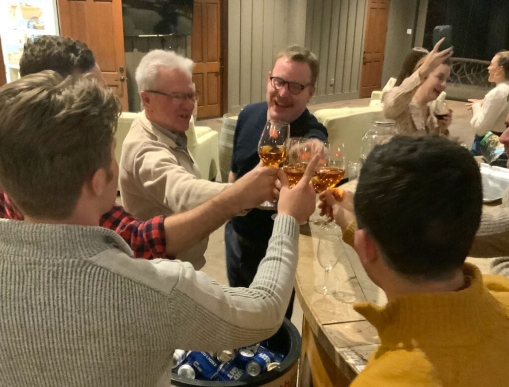 Five men in a circle all toasting with glasses of scotch