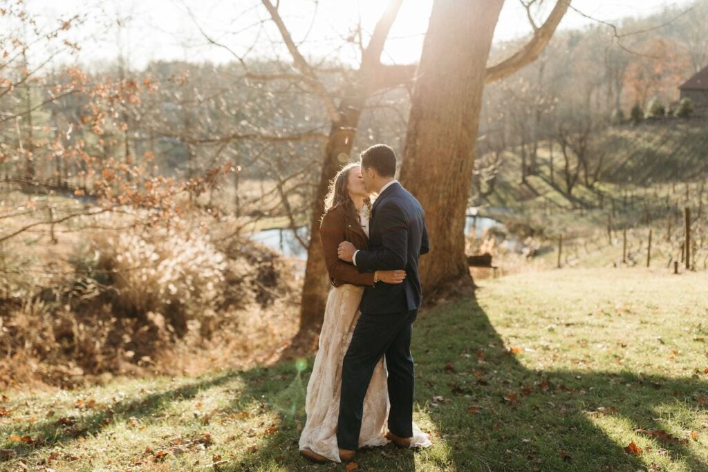 A bride and groom alone in a mountain filed kissing