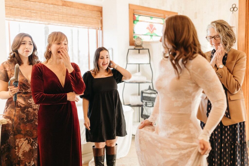 Three best friends see the bride in her dress for the first time - tears and smiles