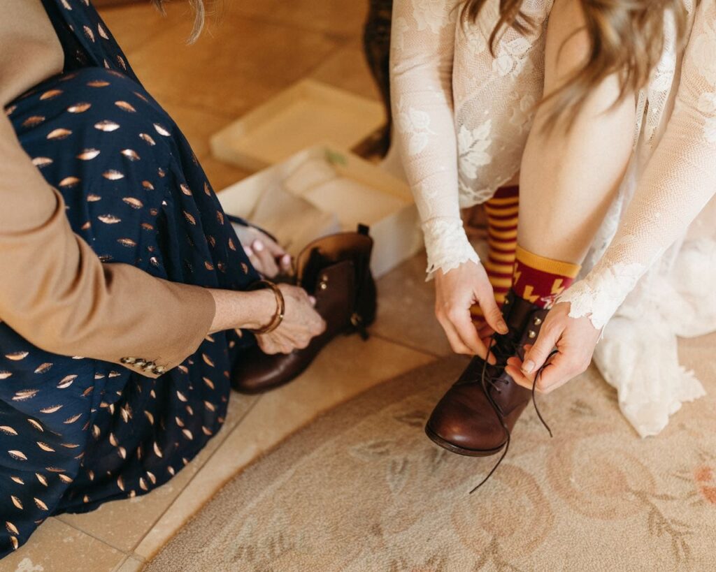 Closeup of mother and daughters hands getting her booties on and tied up