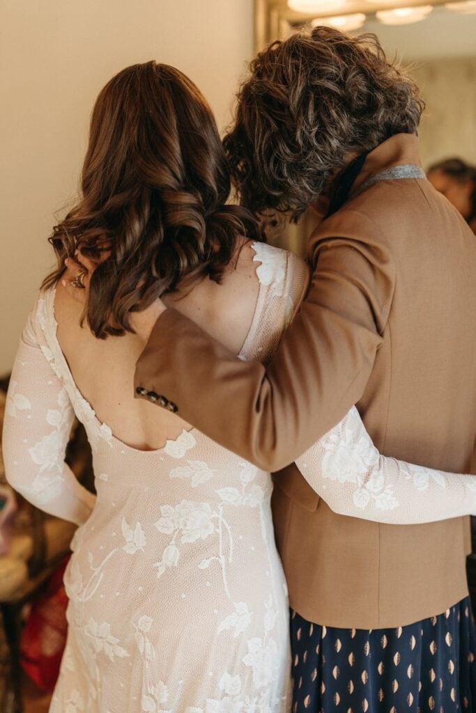 The back of a bride with her mother their arms around each other