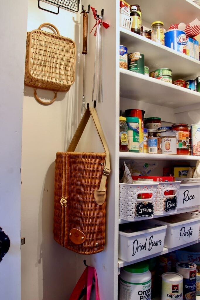 End of the wood shelving on the food side shows hooks on the side holding skewers on one, BBQ fork on another, reuseable grocery bags hanging from another