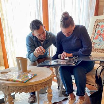 Bride and groom in casual before wedding clothes looking through a large photo album they just received as a gift