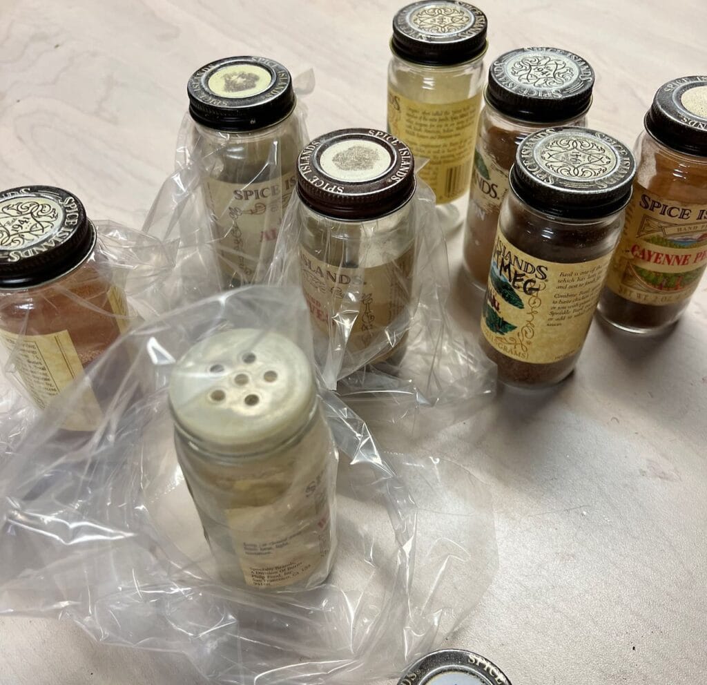 Eight Spice jars are shown with many of them in a plastic sandwich bag and the lid srewed back on over the plastic