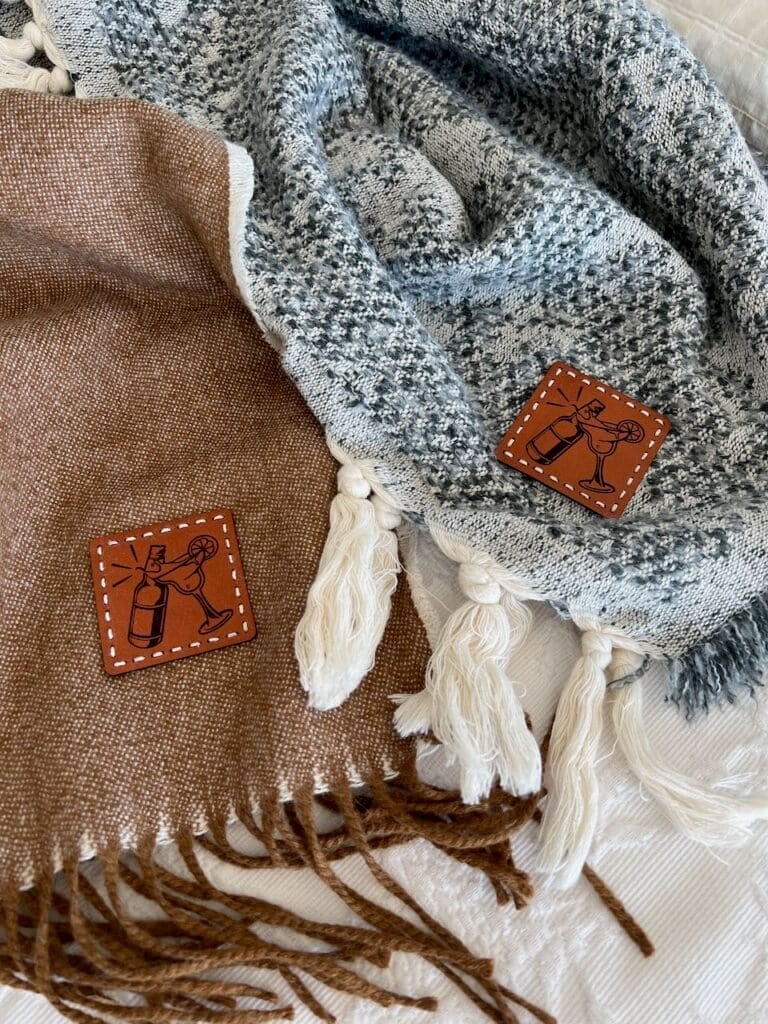 Two cozy fringed throws are lying loosely next to each other with their wedding logo leather patches showing