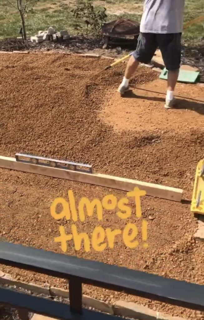 Legs of a man shown standing on the first compacted layer of DG and spreading the new, final layer of DG on top with a caption the reads "almost there"