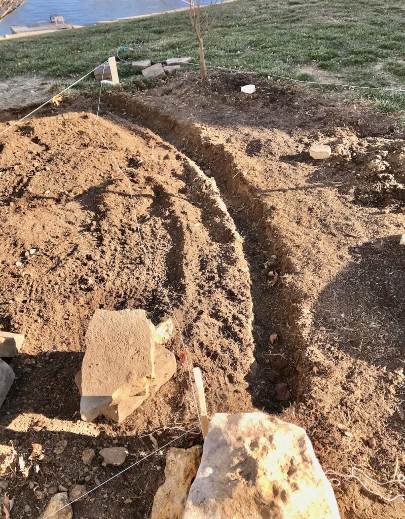 View of a narrow trench dug in the soil to create a curved boundary on the south side