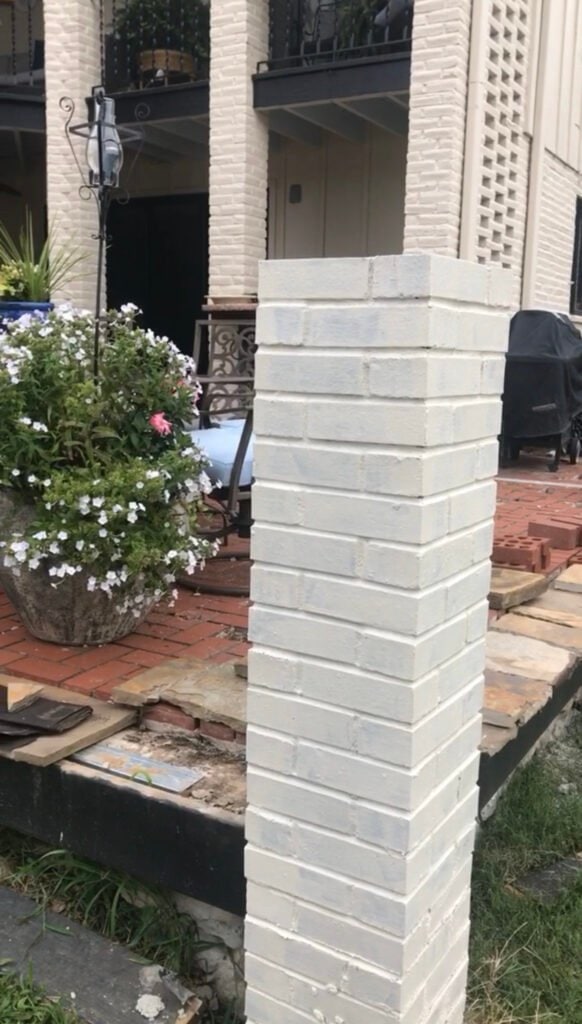 Closeup of new brick post painted with the original brick columns behind