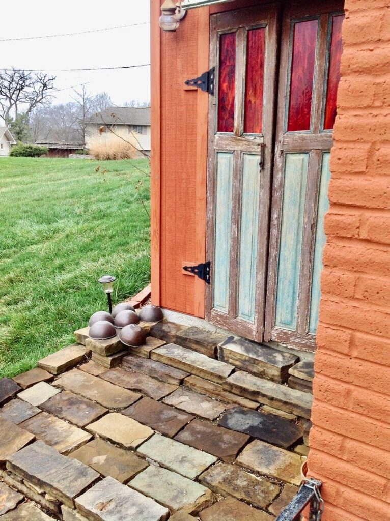 Closeup of the tall doors of the tool shed and the wobbly stone entrance