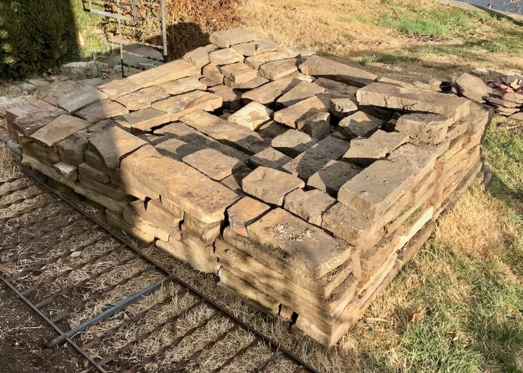 very large pile of flagstone stacked in a square with a long piece of railing beside it.