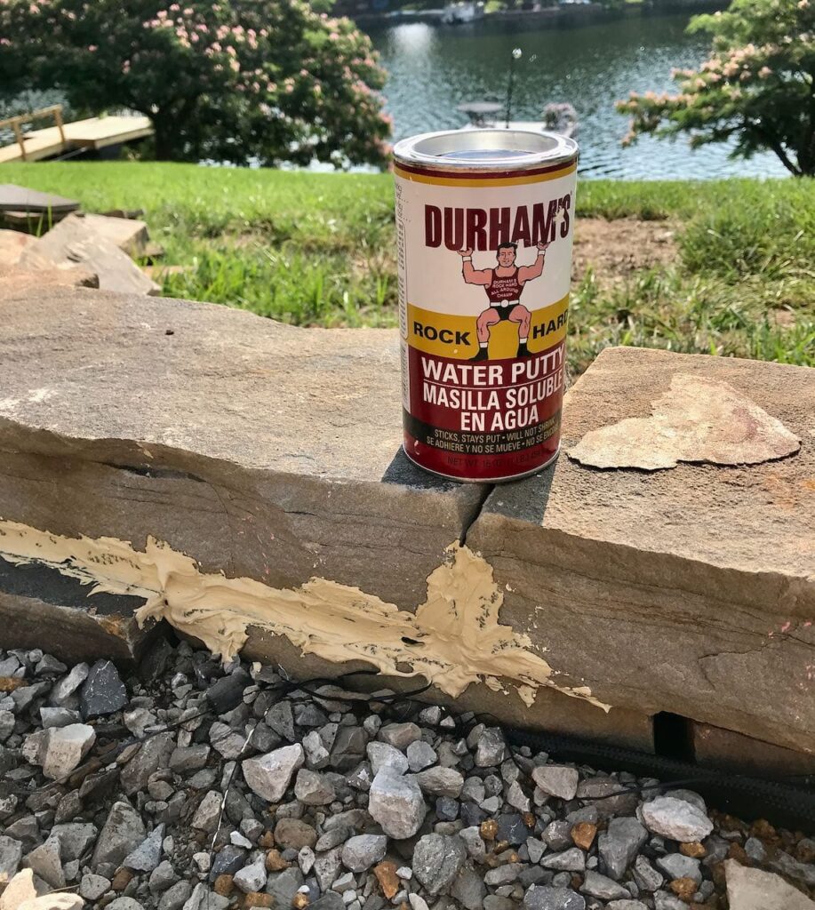 Closeup of a can of Durham's Rock Hard Putty sitting on the stone wall with the seams covered in it showing