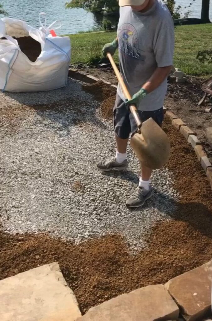 Man shown with a shovel of DG and the partial bag is in the background