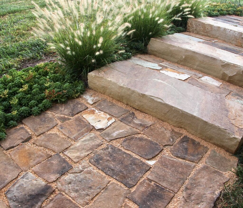 Partial view of the finished flagstone steps and stone walkway with ground cover and decorative grass planted beside