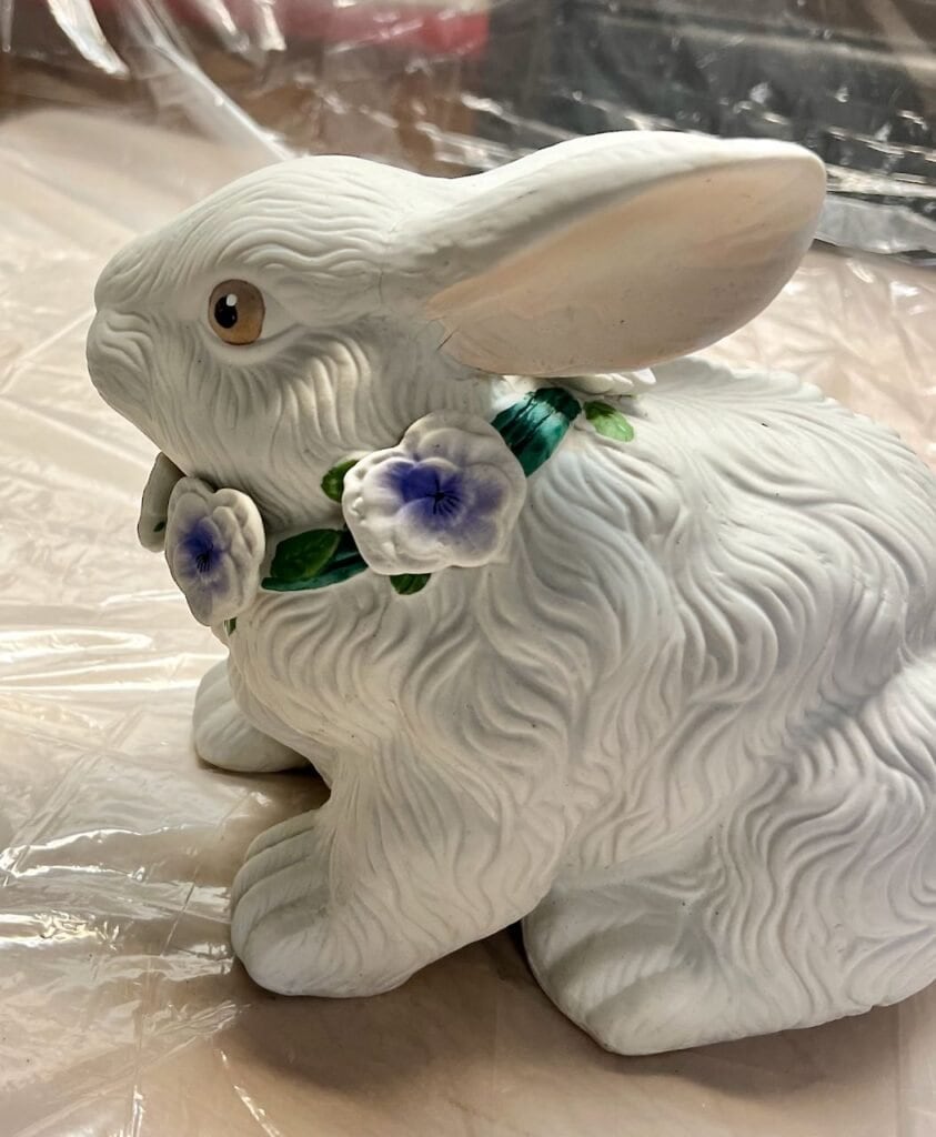 Closeup of bunny statue before her makeover -- complete with bright painted flower necklace and scary painted eyes