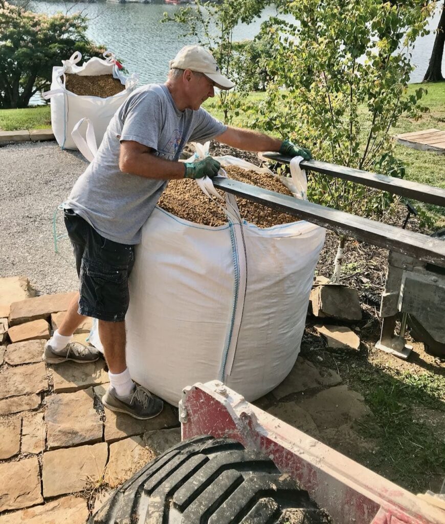 Man shown helping to detach large freight bag of DG from the forklift with a second bag in the background