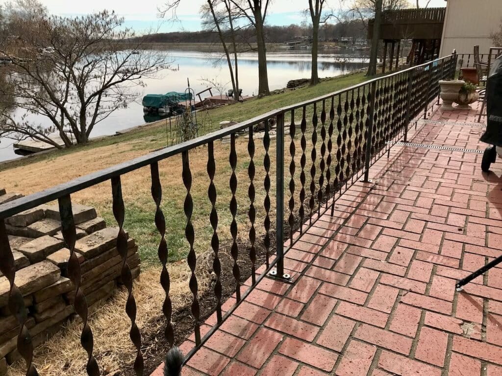 view of. a super long expanse of vintage, short railing installed on a red brick patio